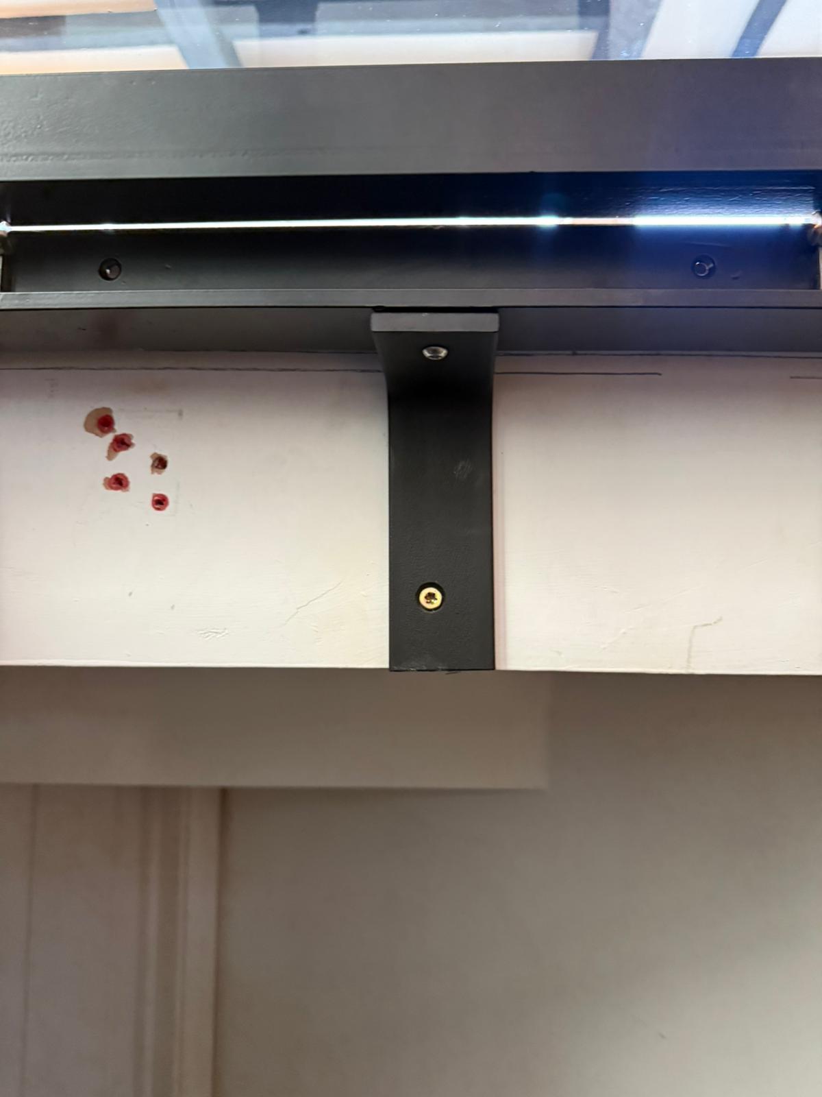 Steel bracket fixing detail showing powder coated black bracket secured to wall supporting hinged glass floor frame, Burwash